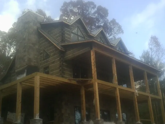 Stone chimney and dormers on a large log home with a timber porch in Elkhart